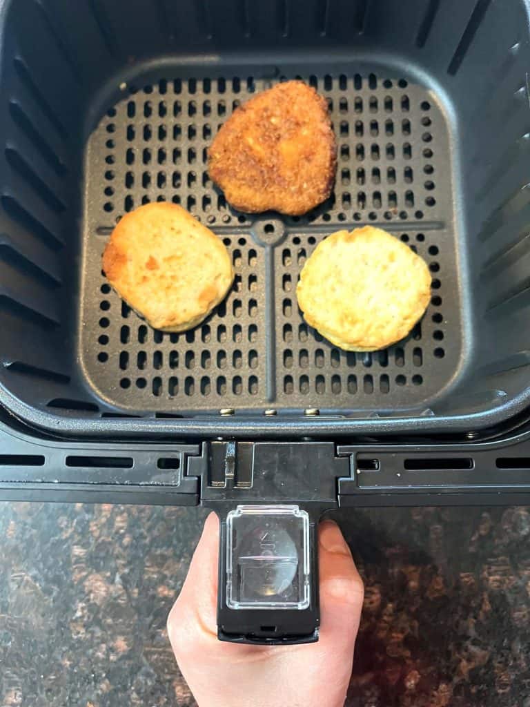 Air fryer basket with three crispy breaded chicken patties, showing the cooking process for a Jimmy Dean Chicken Buttermilk Biscuit Sandwich recipe.