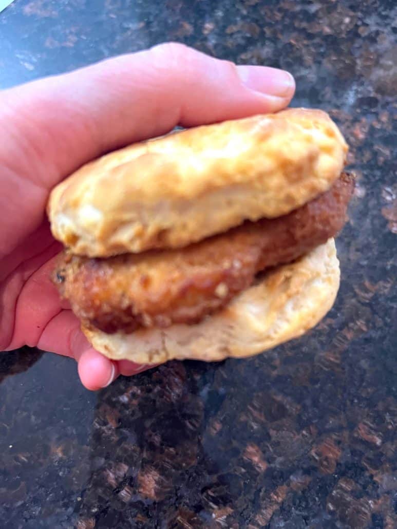 Melanie Mendelson from melaniecooks.com holding a Jimmy Dean Chicken Buttermilk Biscuit Sandwich cooked in the air fryer, with a crispy chicken patty and flaky biscuit.