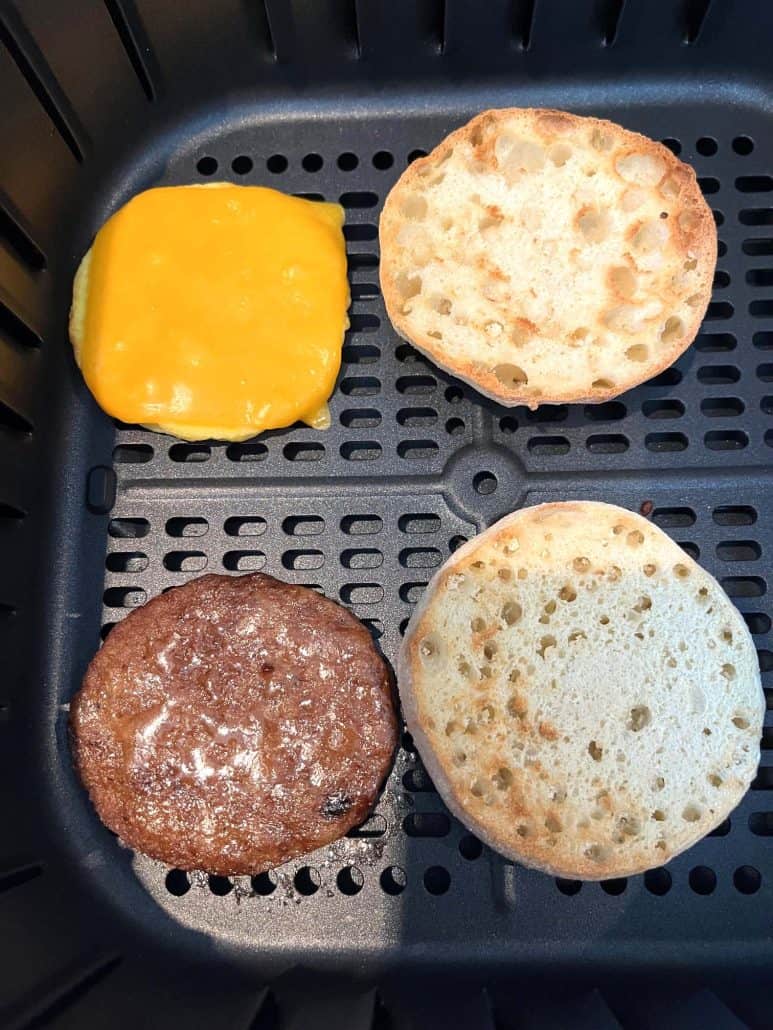 Air fryer basket with a Jimmy Dean English Muffin Sandwich, showing the toasted muffin, sausage, and melted cheese for an evenly cooked breakfast.