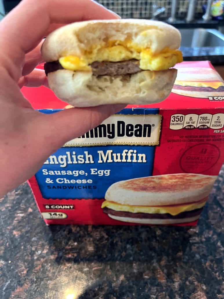 Hand of Melanie Mendelson from melaniecooks.com holding a bite-sized Jimmy Dean English Muffin Sandwich, showing its fluffy texture and crispy muffin.