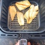 Golden, perfectly cooked orange roughy fillets inside an air fryer basket, showcasing how easy it is to make this delicious fish straight from frozen.