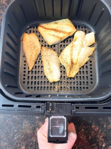 Golden, perfectly cooked orange roughy fillets inside an air fryer basket, showcasing how easy it is to make this delicious fish straight from frozen.