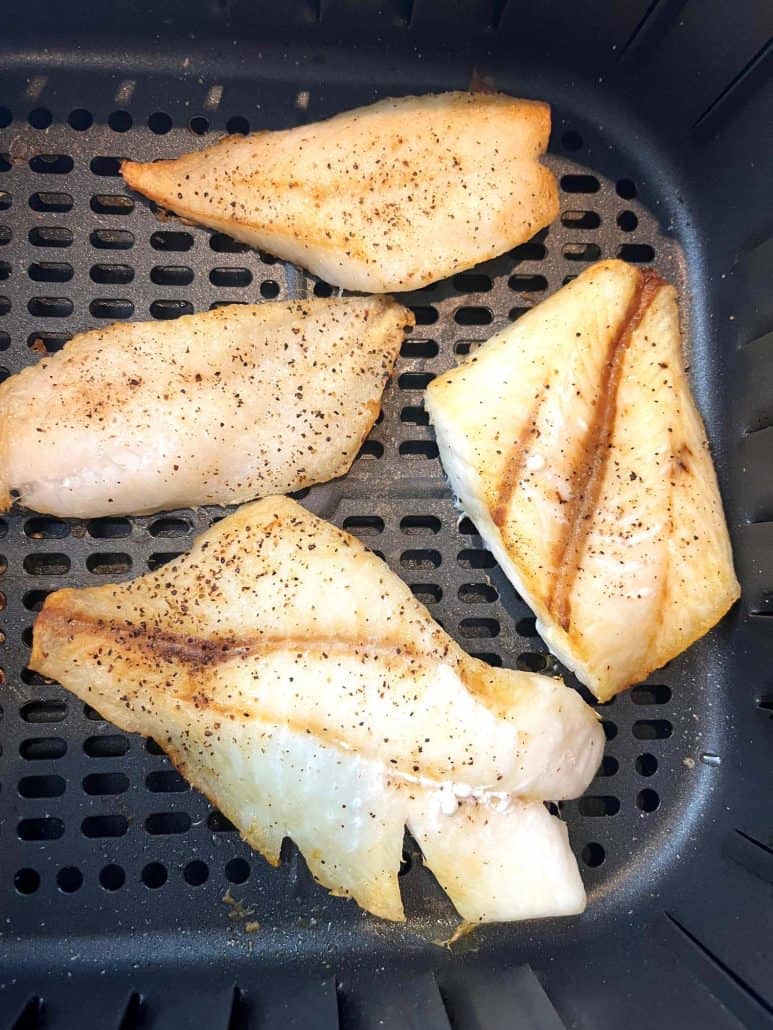 Golden-brown air-fried orange roughy fillets in the air fryer basket, cooked to perfection.