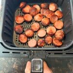 Crispy air-fried ring bologna slices in an air fryer basket, perfectly browned and ready to serve as a delicious appetizer or main dish.