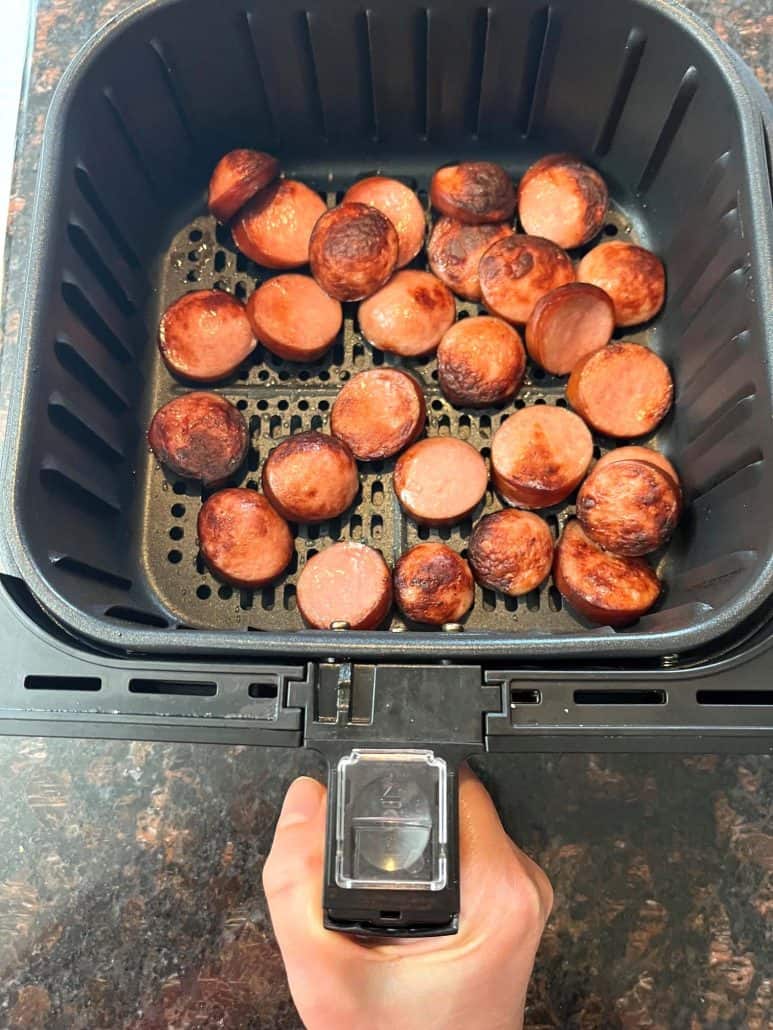 Crispy air-fried ring bologna slices in an air fryer basket, perfectly browned and ready to serve as a delicious appetizer or main dish.