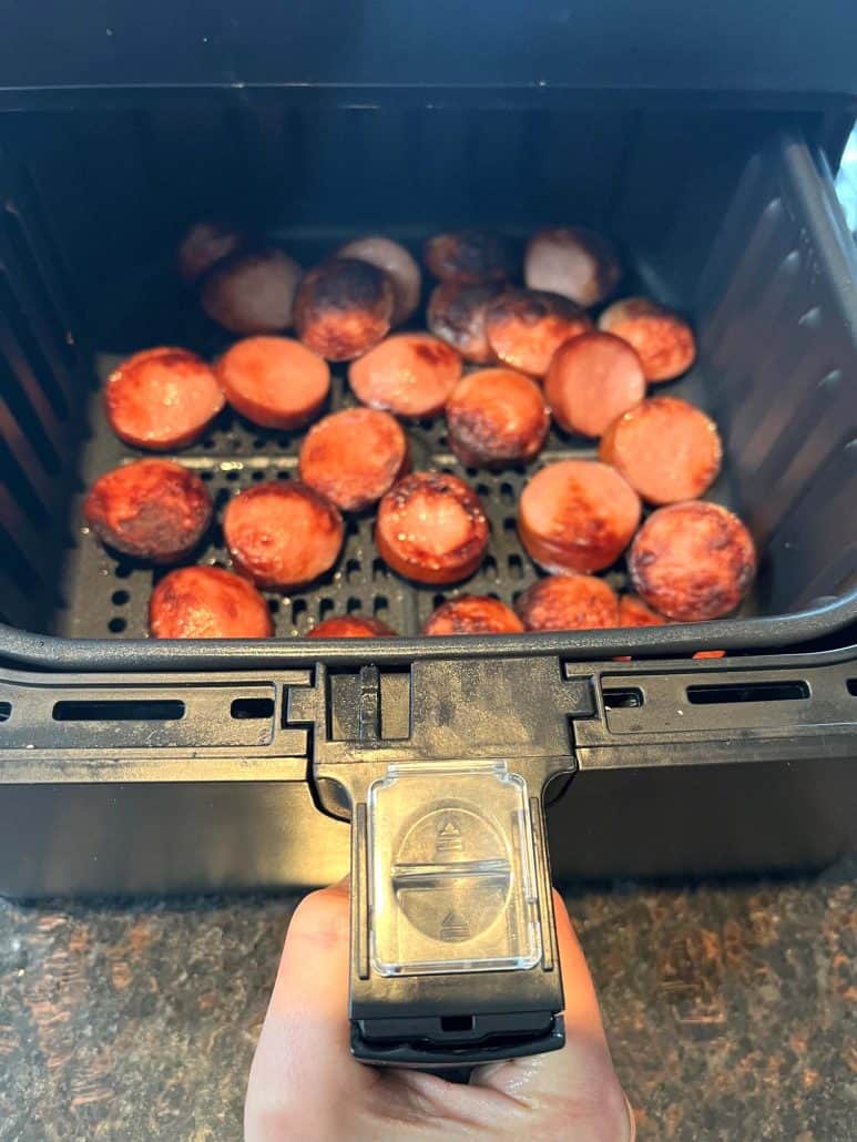 Freshly air-fried ring bologna slices in an air fryer basket, cooked to perfection.