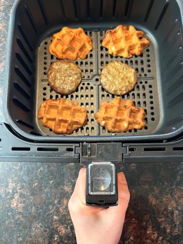 Air fryer basket with crispy waffles and sausage patties cooking separately, showing the best way to make Air Fryer Frozen Sausage Waffle Sandwiches for a perfectly crispy texture.