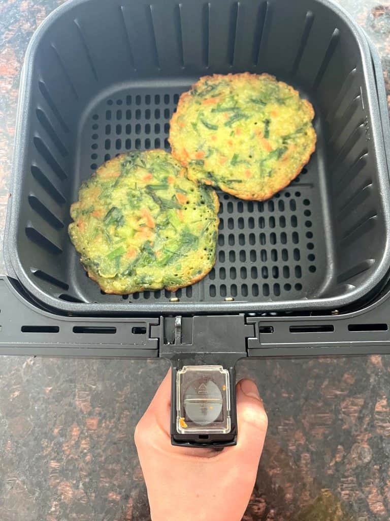 Two cooked Trader Joe’s scallion pancakes in an air fryer basket, showing how they look when finished using the air fryer method.