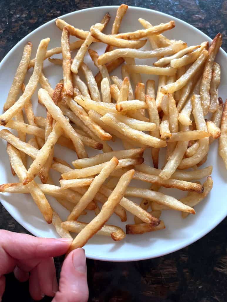 Melanie Mendelson from melaniecooks.com holding a plate of crispy McCain Beer Battered Fries, freshly cooked and ready to serve.